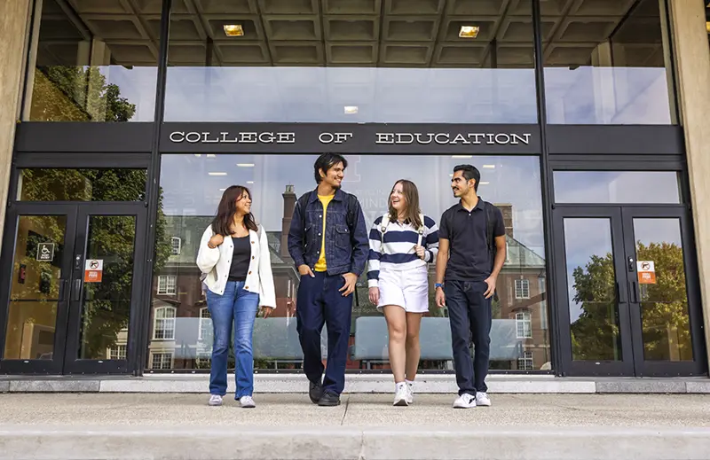 Four diverse students walking from the Education Building.
